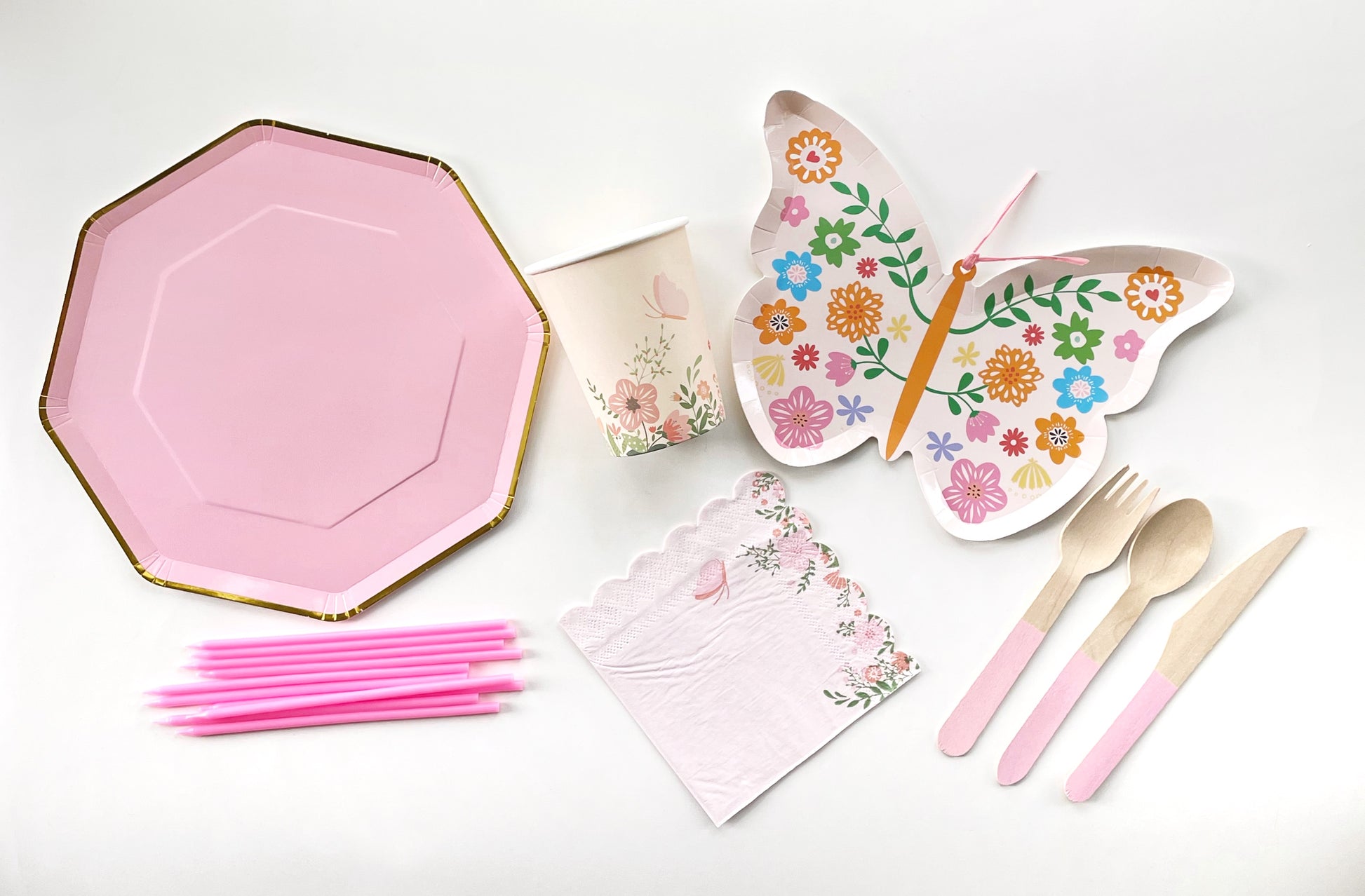 The complete Butterfly Party Kit including large pink and gold paper party plates, small butterfly shaped paper party plates, paper cups, pink paper napkins, pink dipped wooden utensils and tall pink birthday candles. The Butterfly pattern includes pink, gold, blue, green and orange colours. The large party plates are in the shape of an octagon.