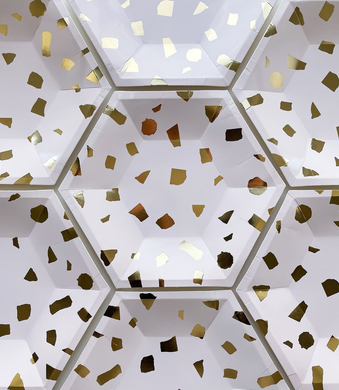 The large paper party plates are in the shape of a hexagon. The plates are a pale blush pink colour with gold foil detail. This image shows multiple plates.