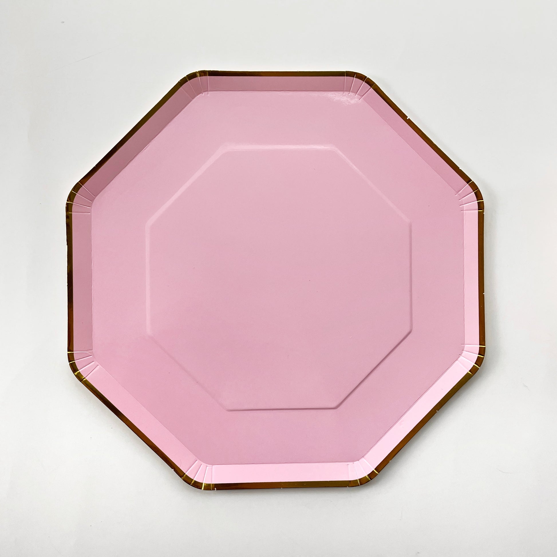 A large pink and gold paper party plate. The large party plates are in the shape of an octagon.