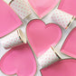 Bright pink heart shaped party plates, with a gold foil edge. White and pink paper party cups with a pink heart pattern.
