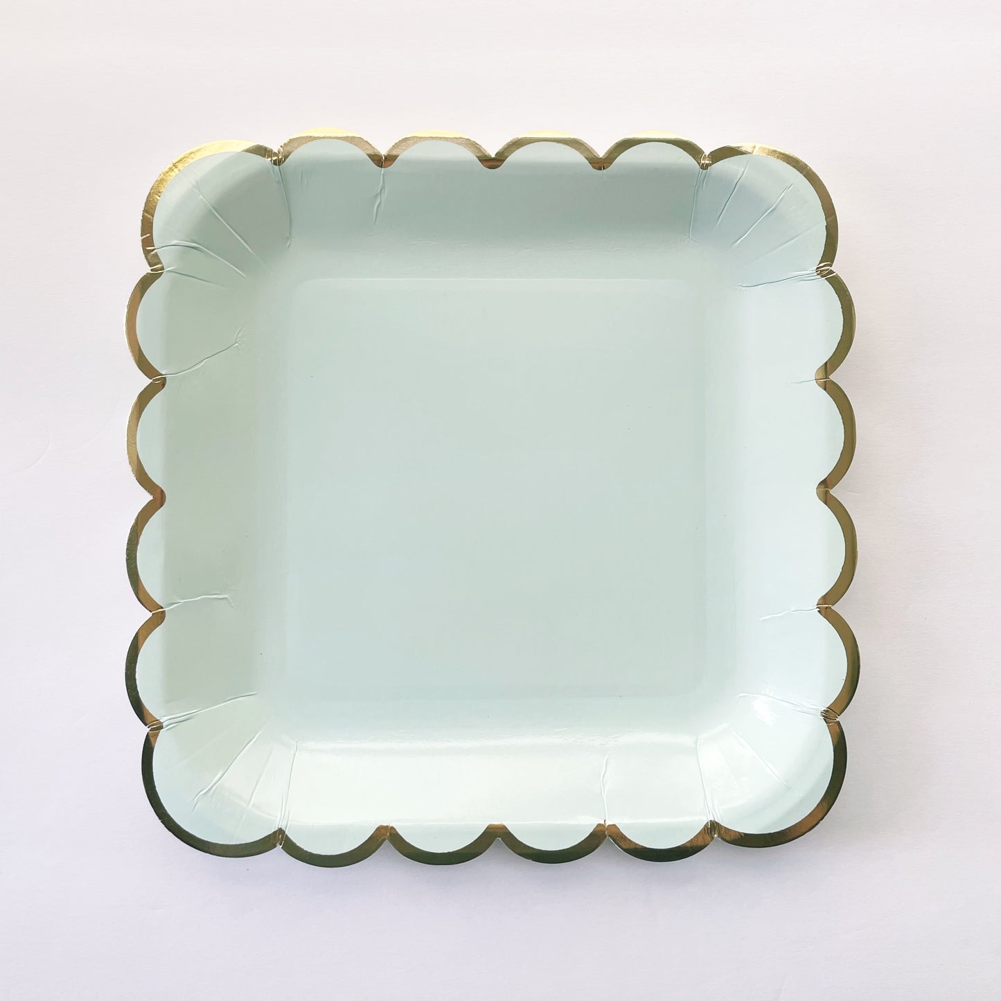 The large paper party plates are in the shape of a square. The plates are a pale pastel blue colour with gold foil scalloped trim.
