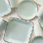 Paper party plates and cups. They are a pale pastel blue colour with gold foil scalloped trim.