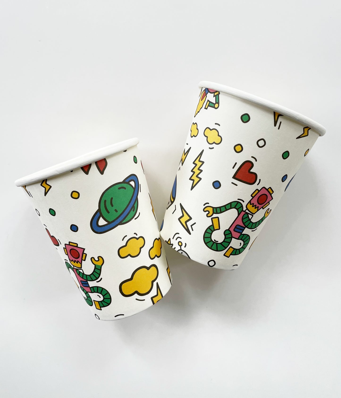 Paper party cups feature a fun and colourful pattern including planets, robots, spaceships and clouds in green, blue, red, yellow and pink colours.