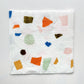 The paper party cocktail napkins feature a terrazzo pattern including blue, orange and green colours with gold foil detail.