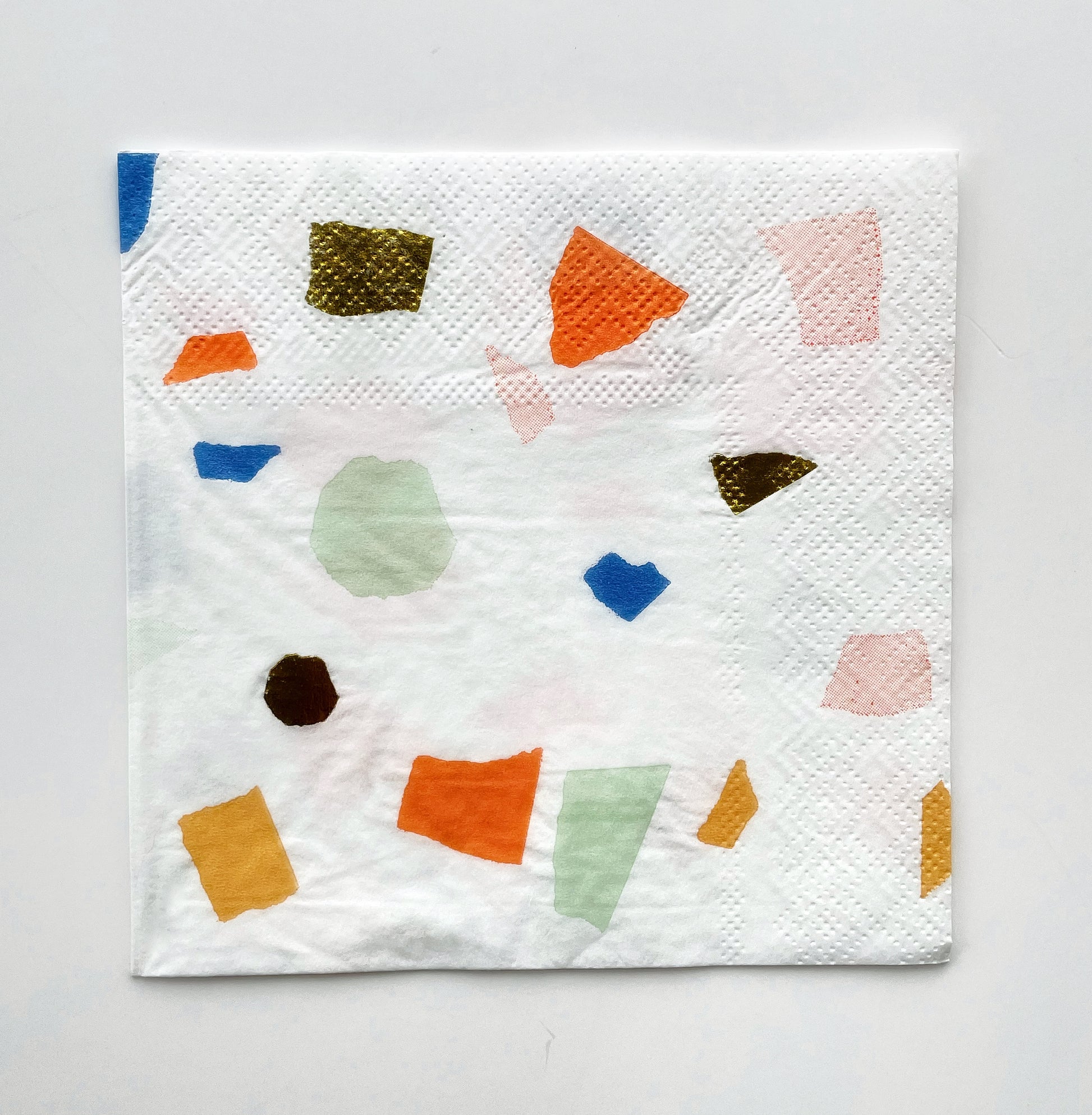 The paper party cocktail napkins feature a terrazzo pattern including blue, orange and green colours with gold foil detail.