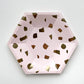 The small paper party plates are in the shape of a hexagon. The plates are a pale blush pink colour with gold foil detail.