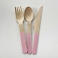 Pink dipped wooden utensils. This cutlery set includes knives, spoons and forks.