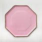 A large pink and gold paper party plate. The large party plates are in the shape of an octagon.