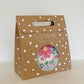 The Blossom Party Kit in its kraft brown and white carry box. The box features a handle and a circular opening where you can see the contents inside.
