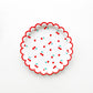The small Cherry paper party plates have a red scalloped edge. The cherry pattern includes red, white and green colours.  
