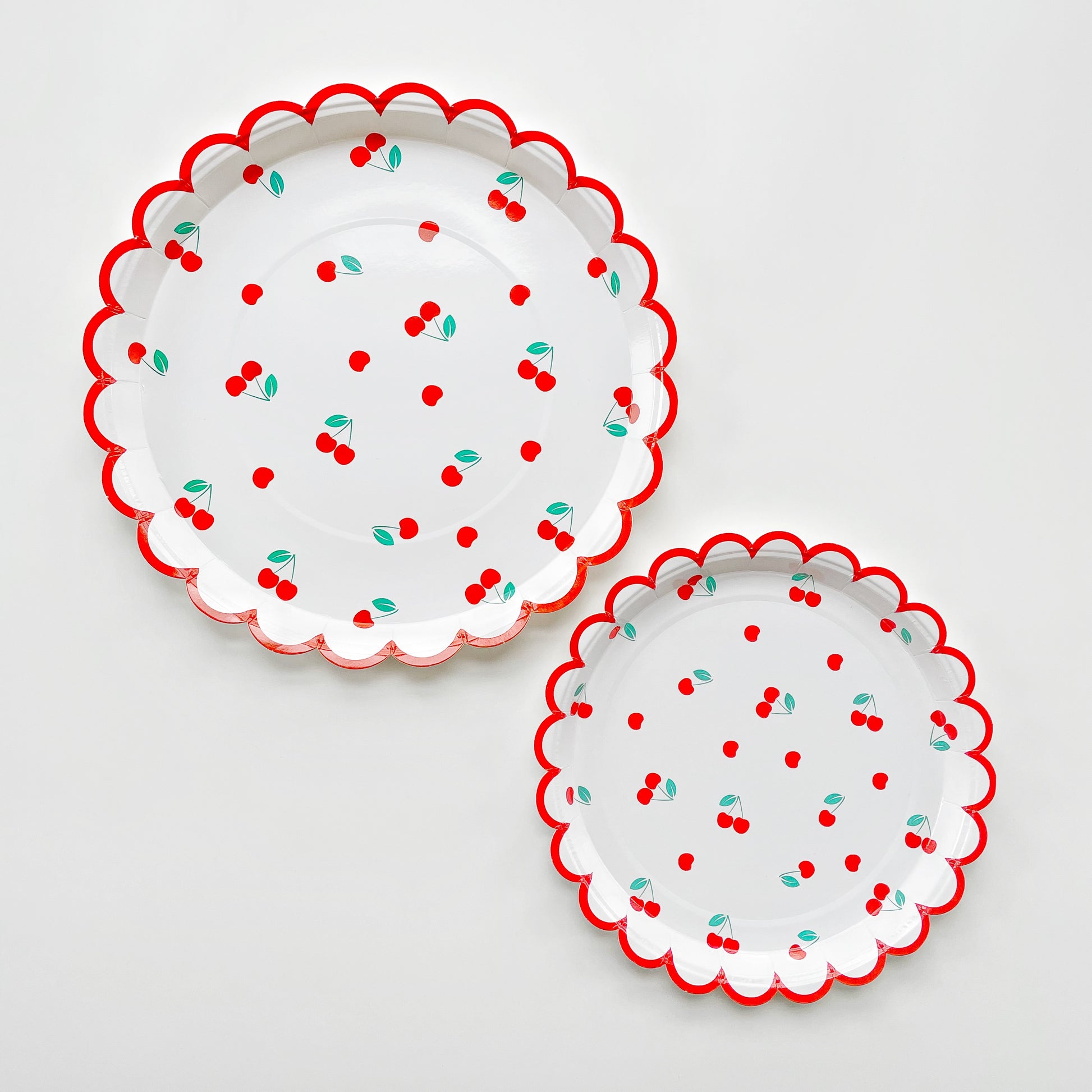 The large and small Cherry paper party plates have a red scalloped edge. The cherry pattern includes red, white and green colours.  