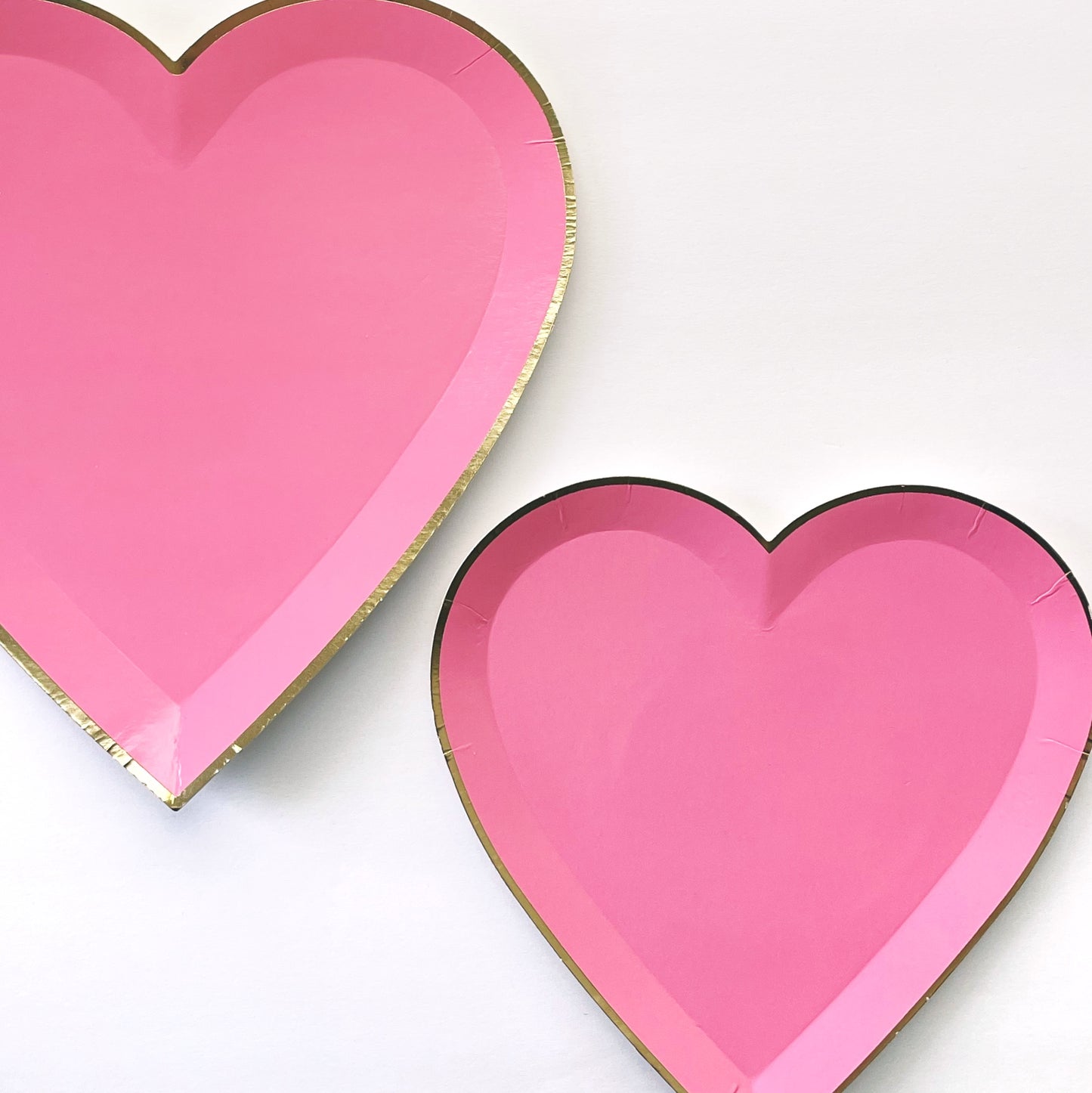 Bright pink heart shaped large and small party plates, with a gold foil edge.