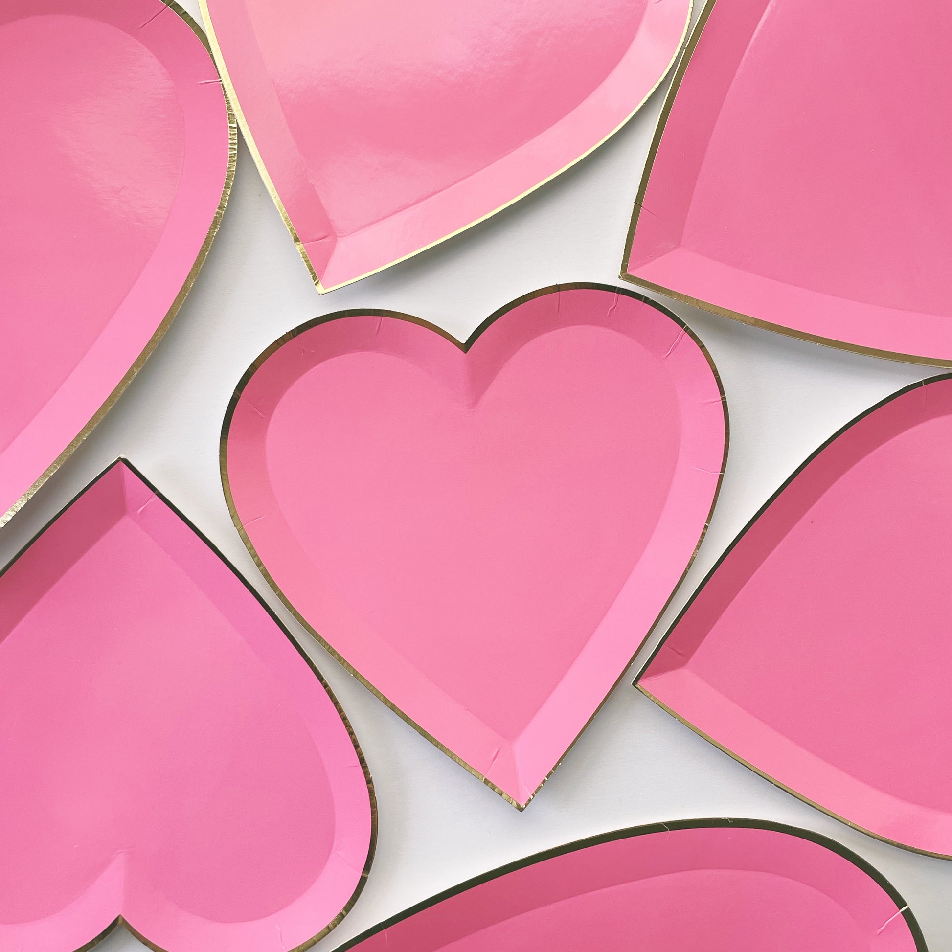Bright pink heart shaped party plates, with a gold foil edge.