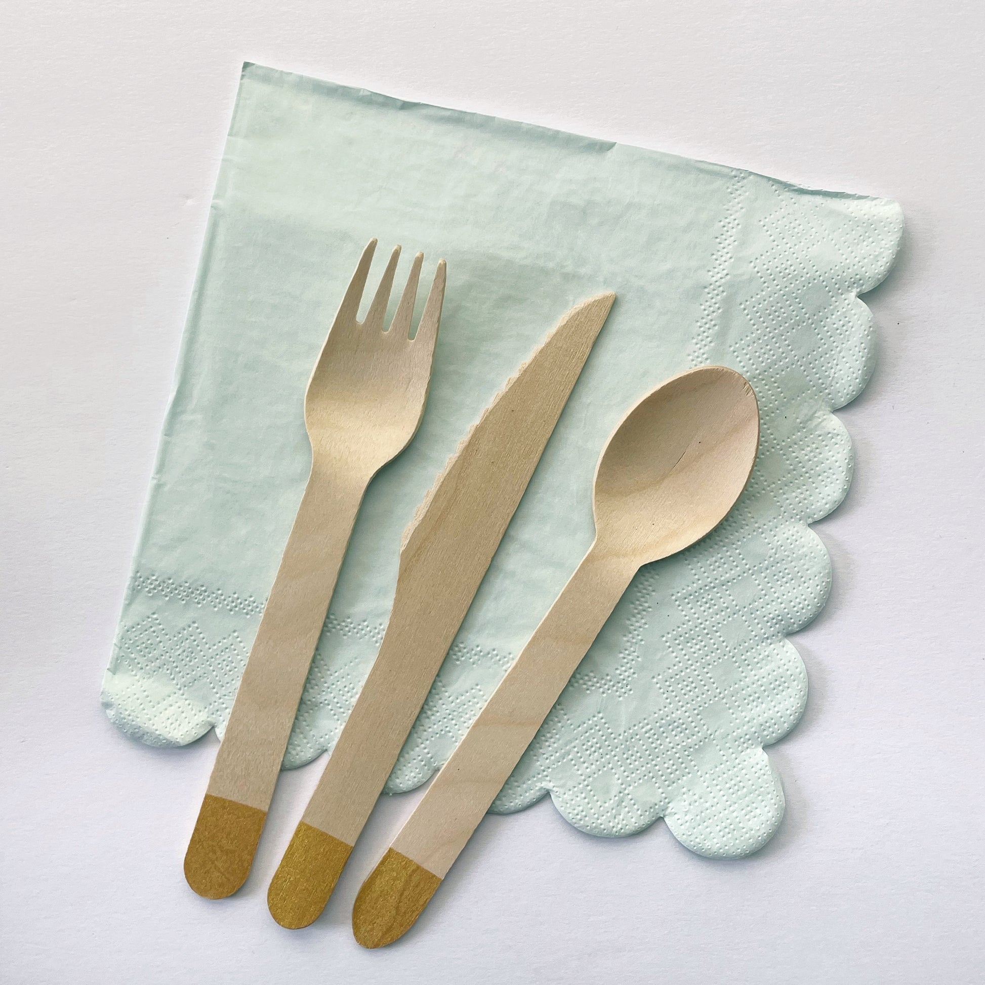 Pale pastel blue paper party napkins with a scalloped trim. Gold dipped wooden utenils.
