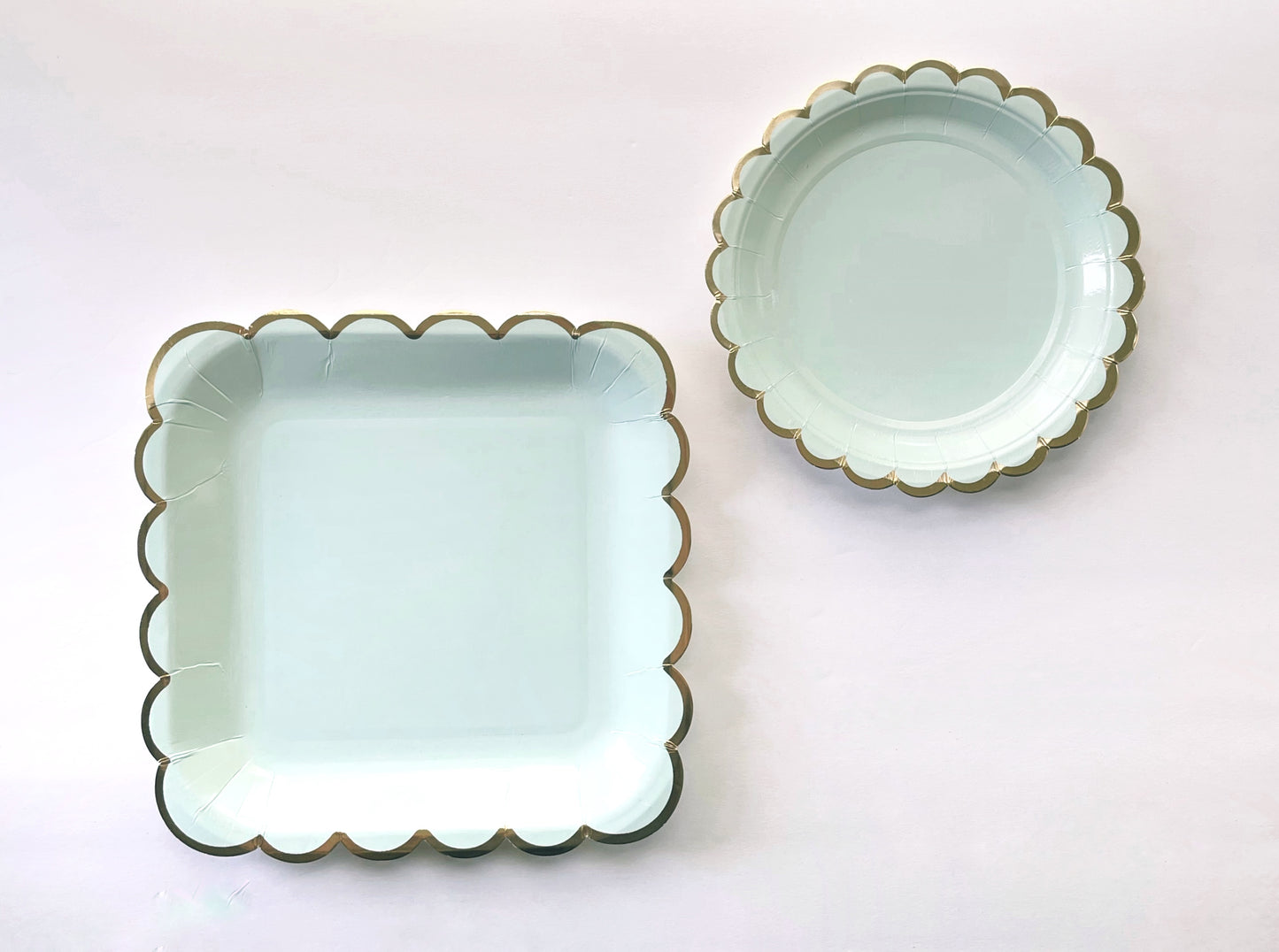 The large and small paper party plates. The plates are a pale pastel blue colour with gold foil scalloped trim.