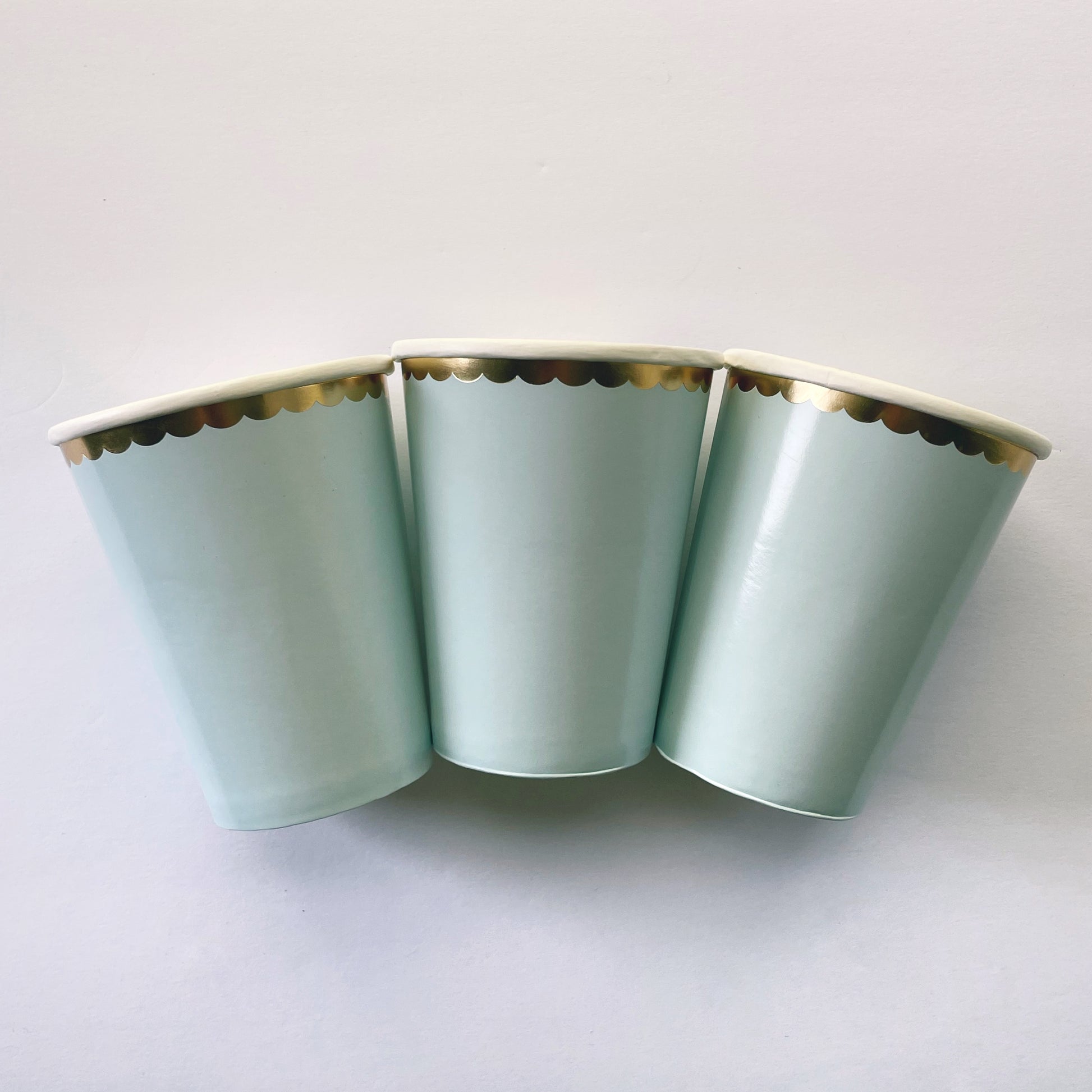 The paper party cups are a pale pastel blue colour with gold foil detail.