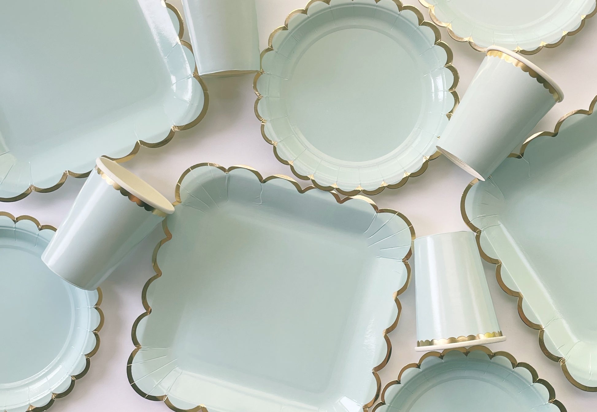 Paper party plates and cups. They are a pale pastel blue colour with gold foil scalloped trim.