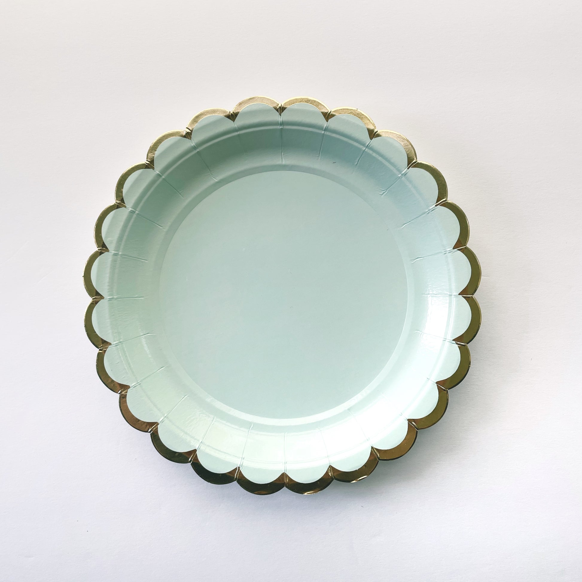 The small paper party plates are in the shape of a circle. The plates are a pale pastel blue colour with gold foil scalloped trim.