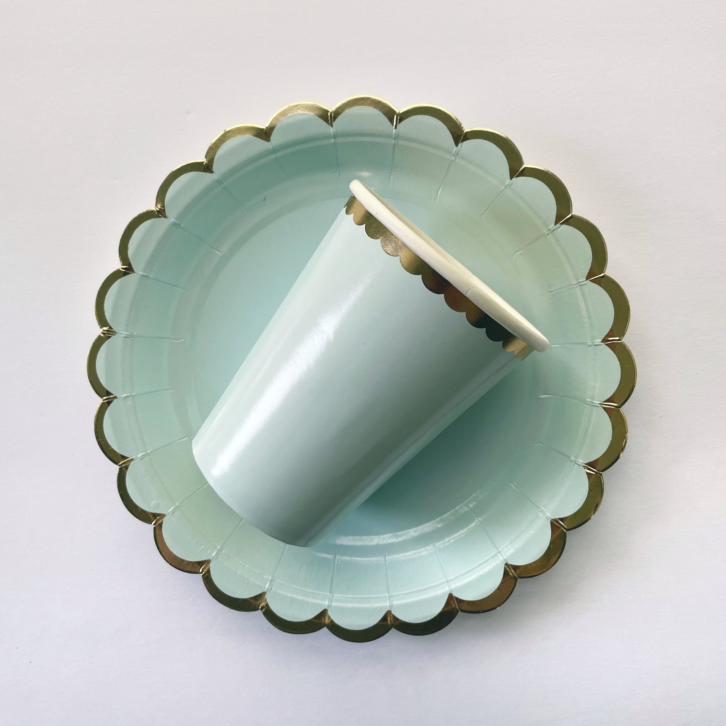 Small paper party plates and party cups. They are a pale pastel blue colour with gold foil scalloped trim.