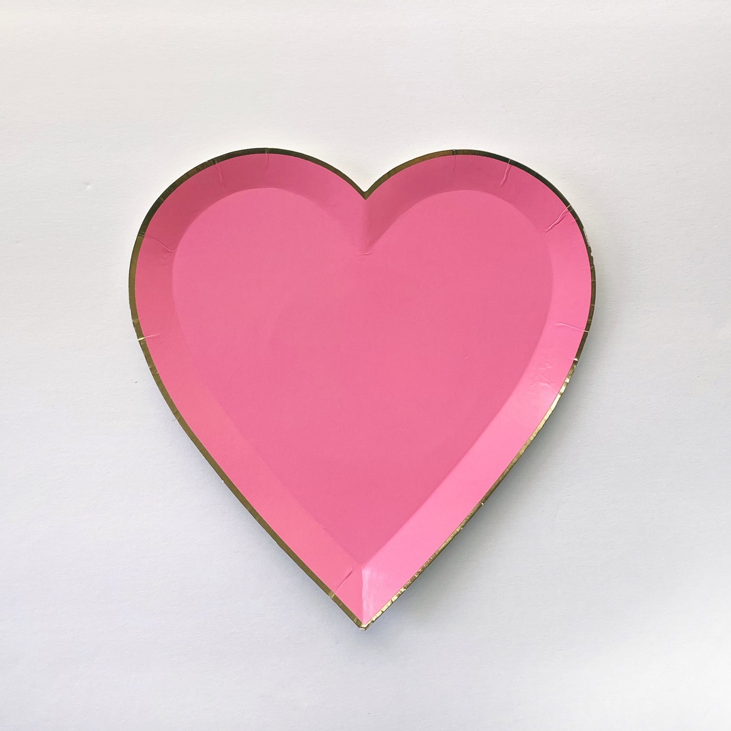 Bright pink heart shaped small party plate, with a gold foil edge.