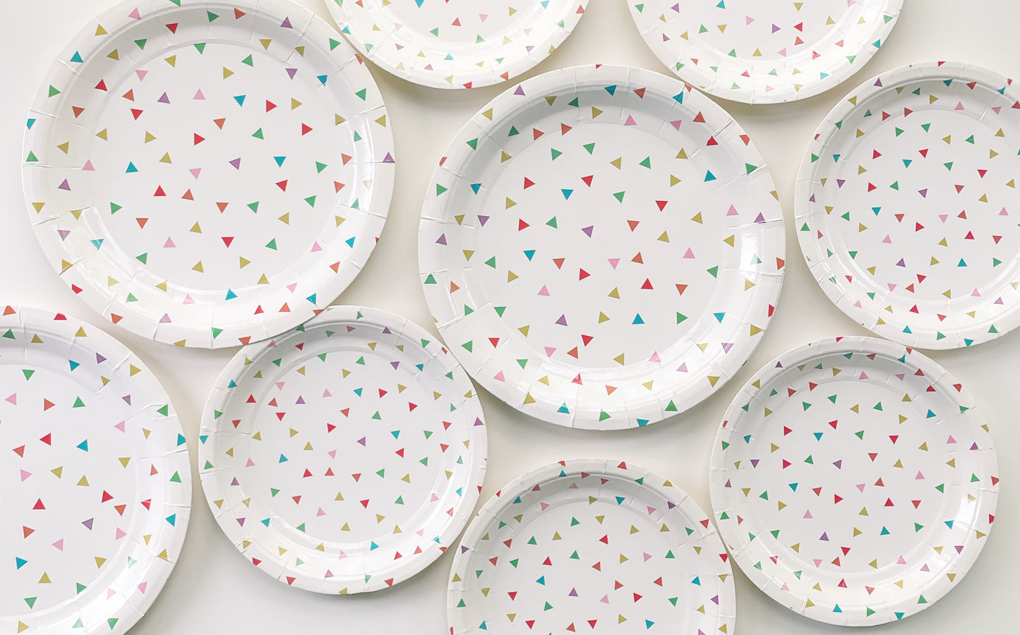 Large and small paper plates with a triangle pattern featuring green, orange, pink, blue and yellow colours.