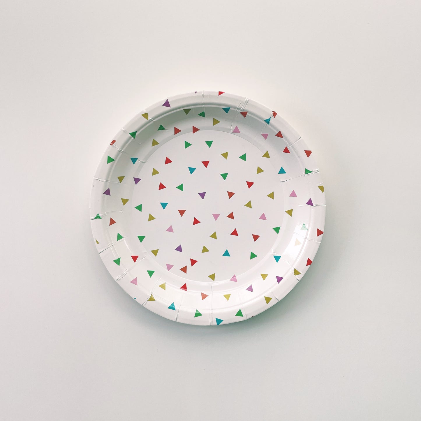 Small paper plates with a triangle pattern featuring green, orange, pink, blue and yellow colours.