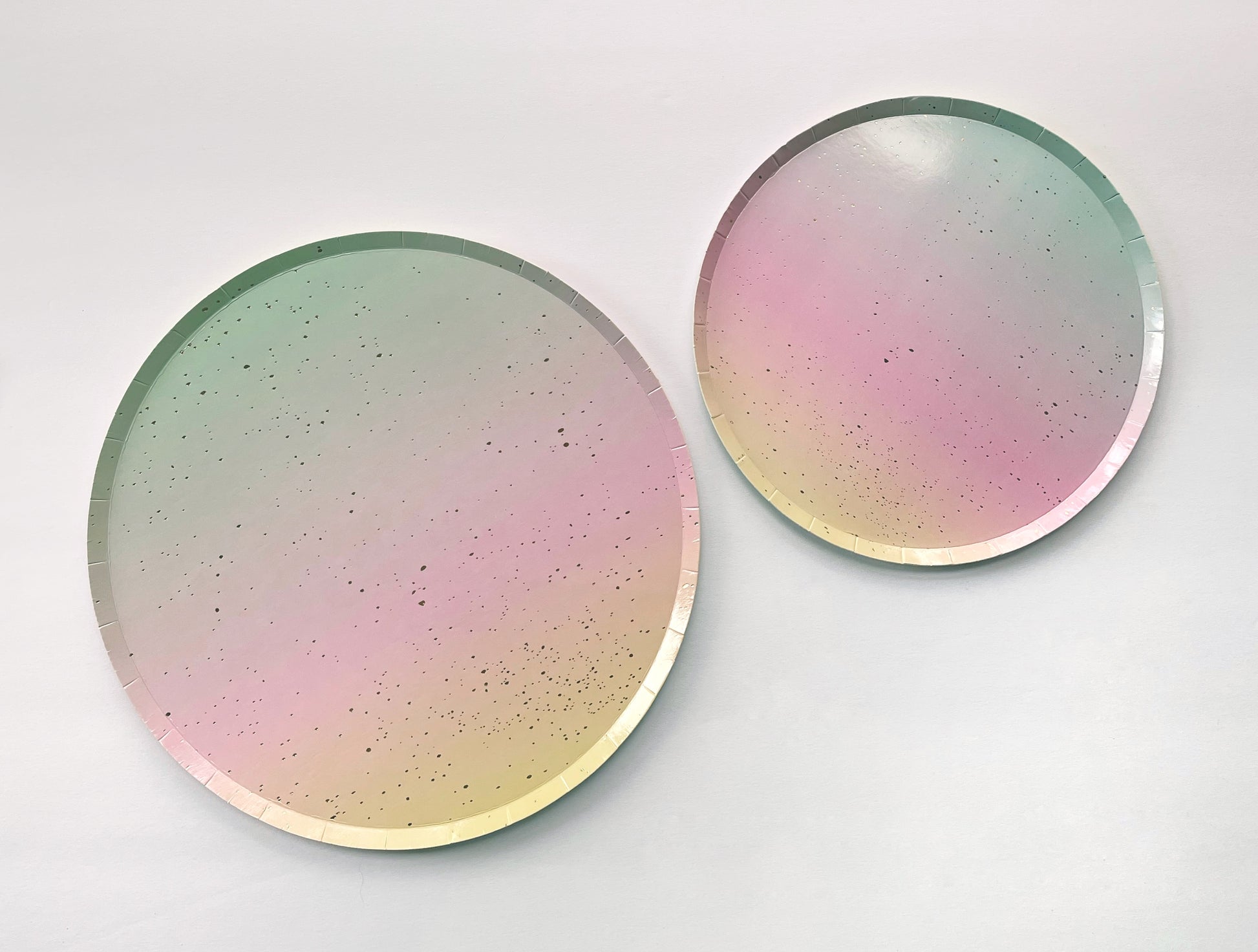 The Ombre Party Kit's large and small circular pink, yellow, green and gold paper party plates.