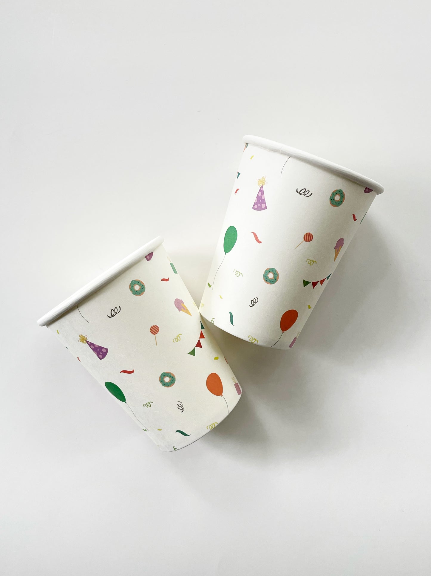 The Celebration paper party cups feature green, orange and blue balloons, ice cream cones, party hats, party garlands, birthday gifts and donuts.