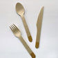 Gold dipped wooden utensils. This cutlery set includes knives, spoons and forks.