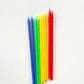 Ten tall rainbow birthday cake candles in yellow, red, green and blue.