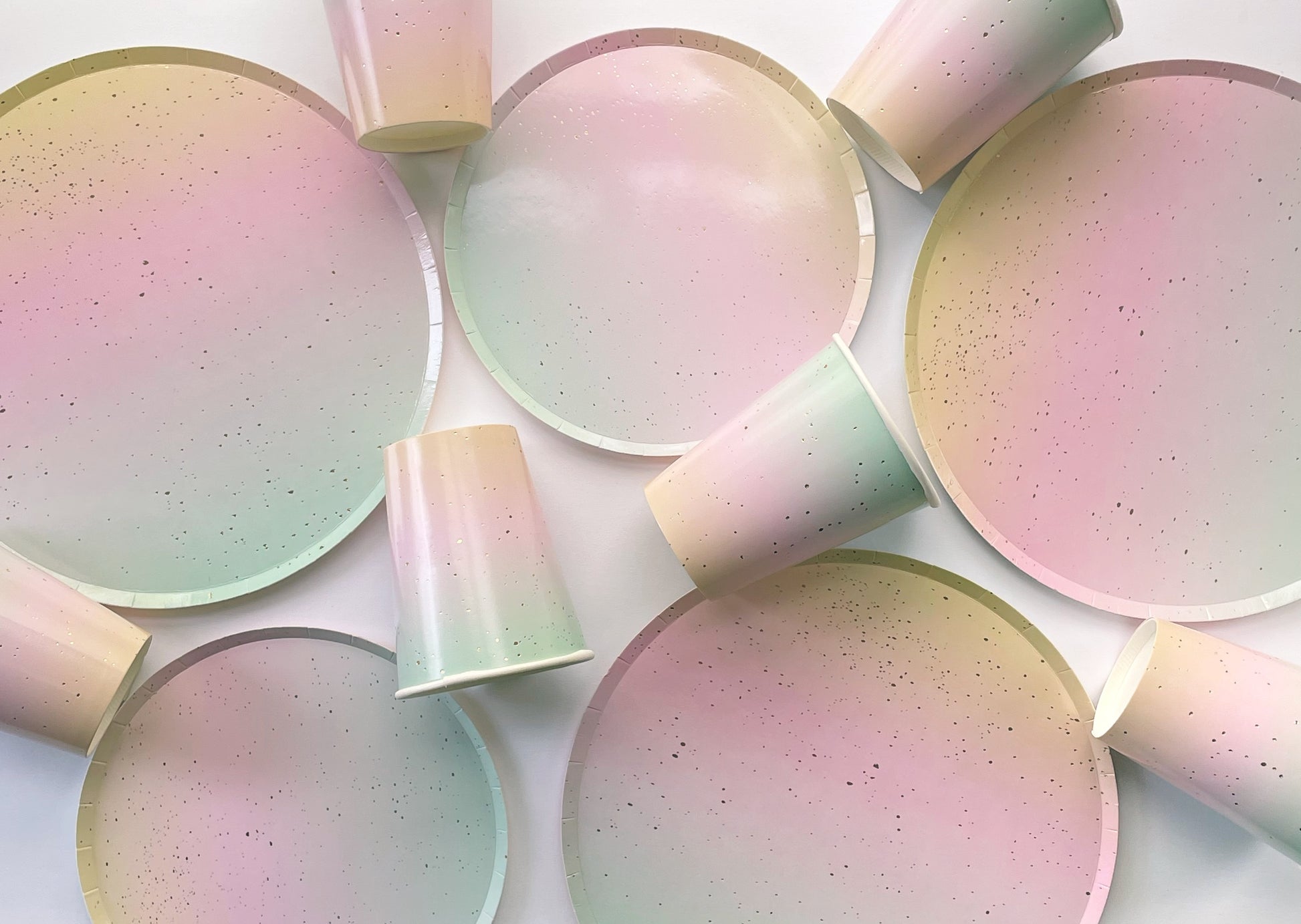 The Ombre Party Kit's large and small circular pink, yellow, green and gold paper party plates and cups.