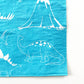 Close up of the blue and white paper party napkins. The dinosaur pattern features green, blue, yellow and red dinosaurs, volcanoes and palm trees
